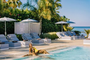 Una piscina techada, una piscina al aire libre, sombrillas