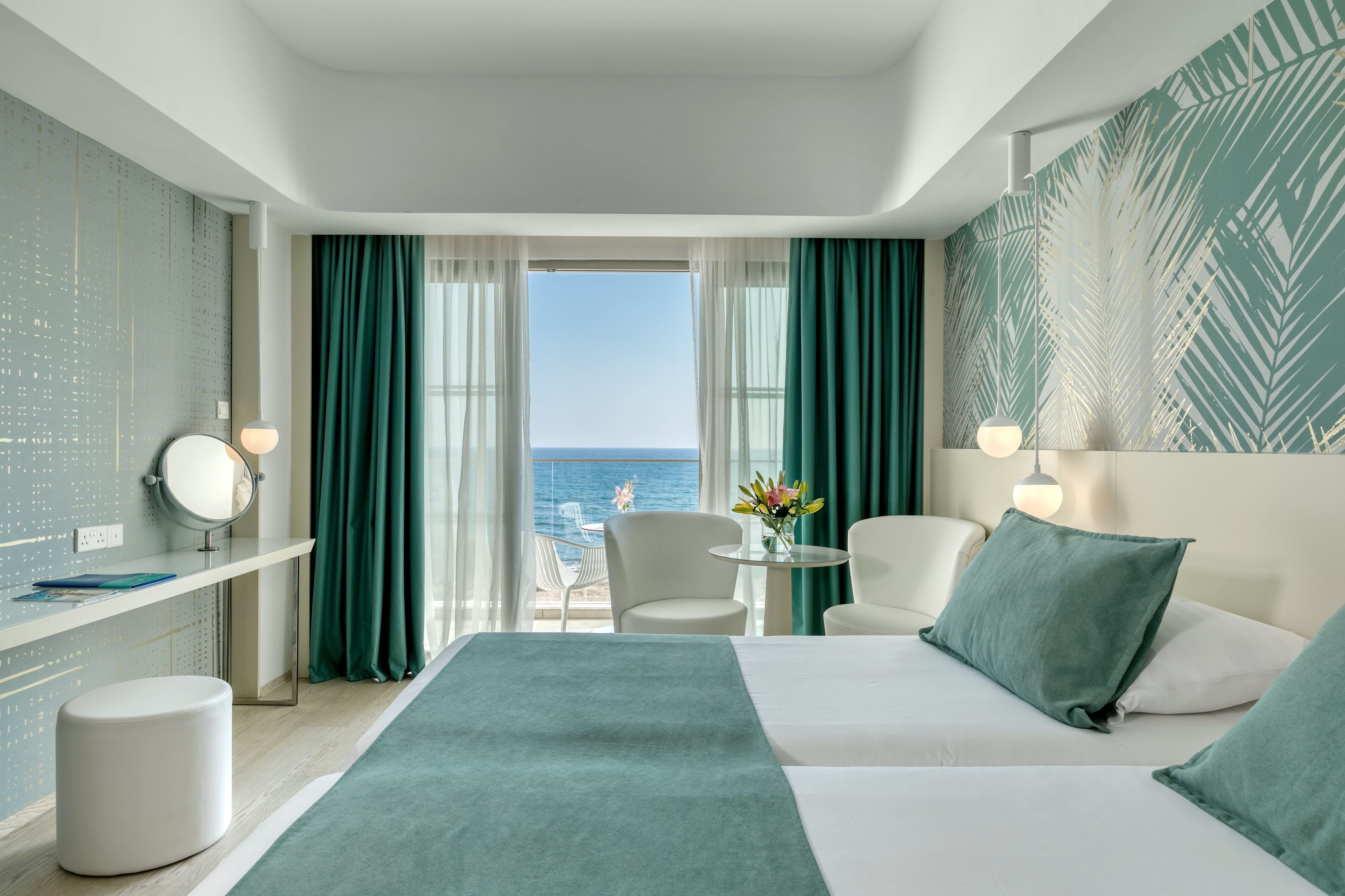 Habitación de hotel con cama, escritorio, silla y vista al mar.