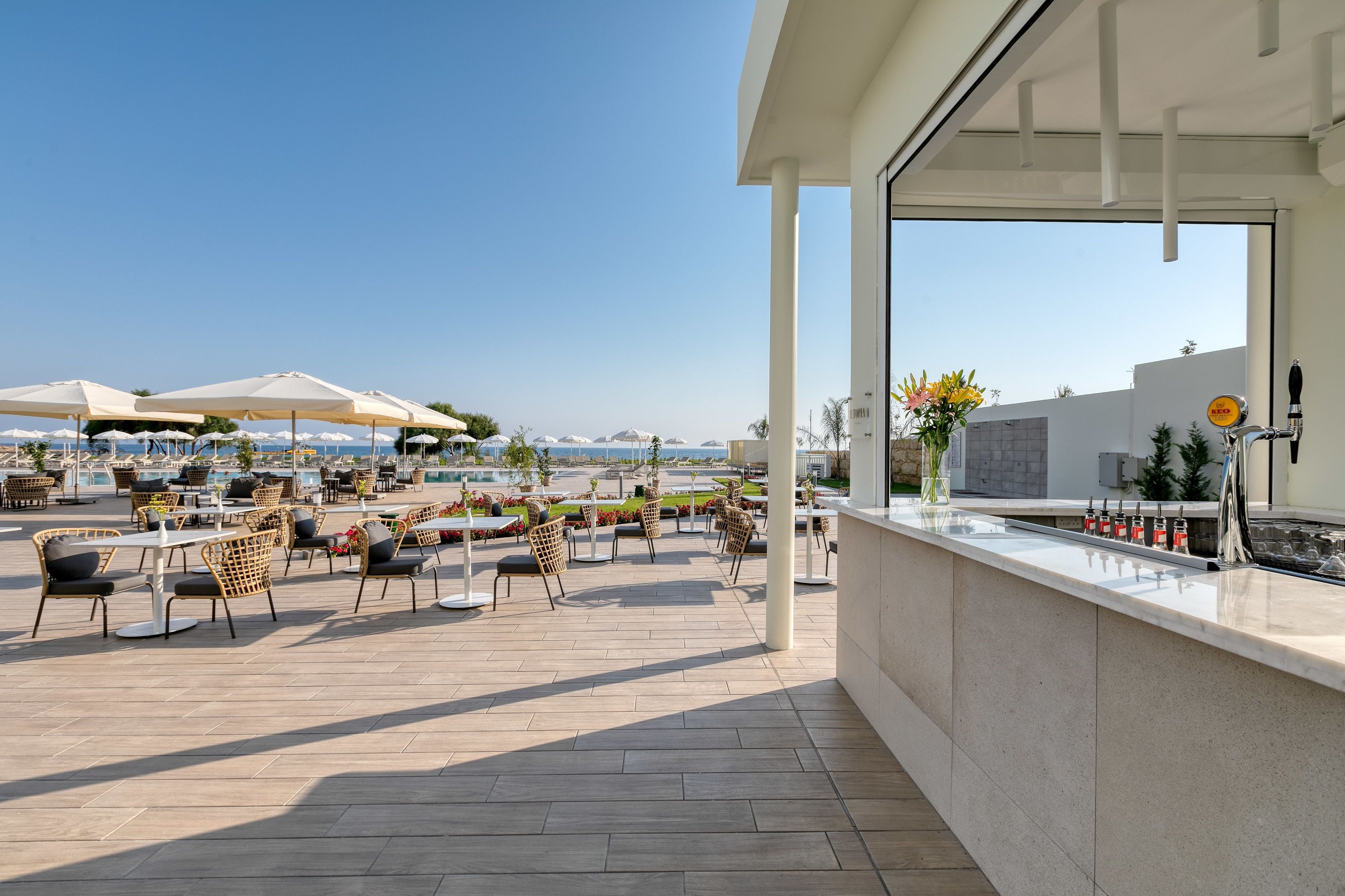 An outdoor patio with tables and chairs, a bar area, and umbrellas.