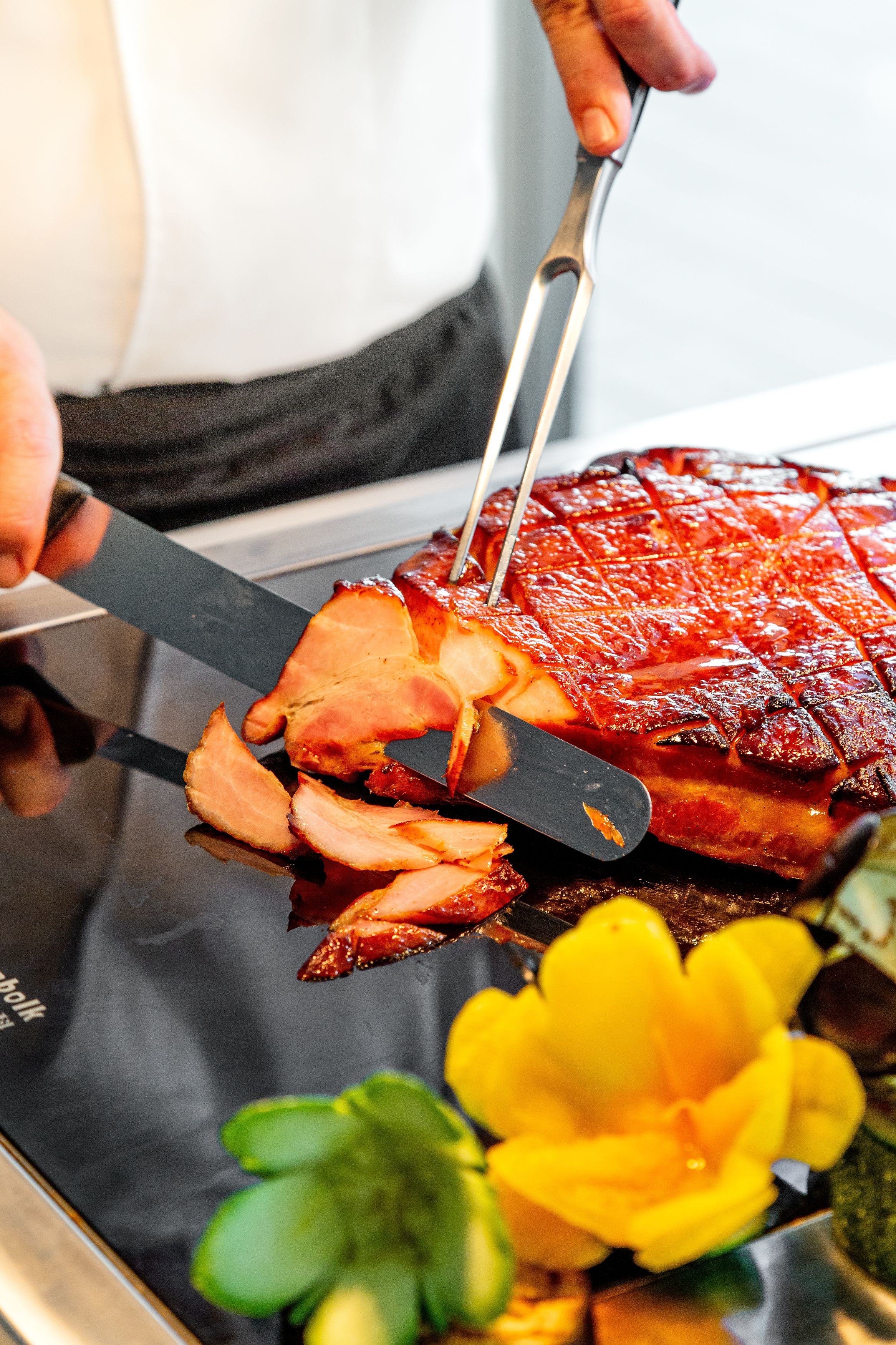 A person slicing a glazed ham with a knife.