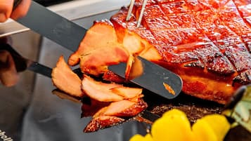 A person slicing a glazed ham with a knife.