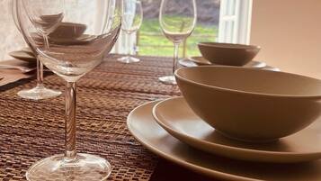 A dining table with a clear glass wine glass, a white bowl, and a plate.