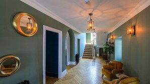 A hallway with a herringbone floor, a staircase, and a seating area with yellow chairs. - Picton House Hotel (Carmarthen)
