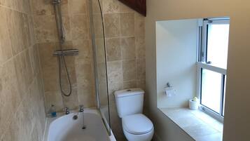 Un baño con bañera, inodoro y ventana.