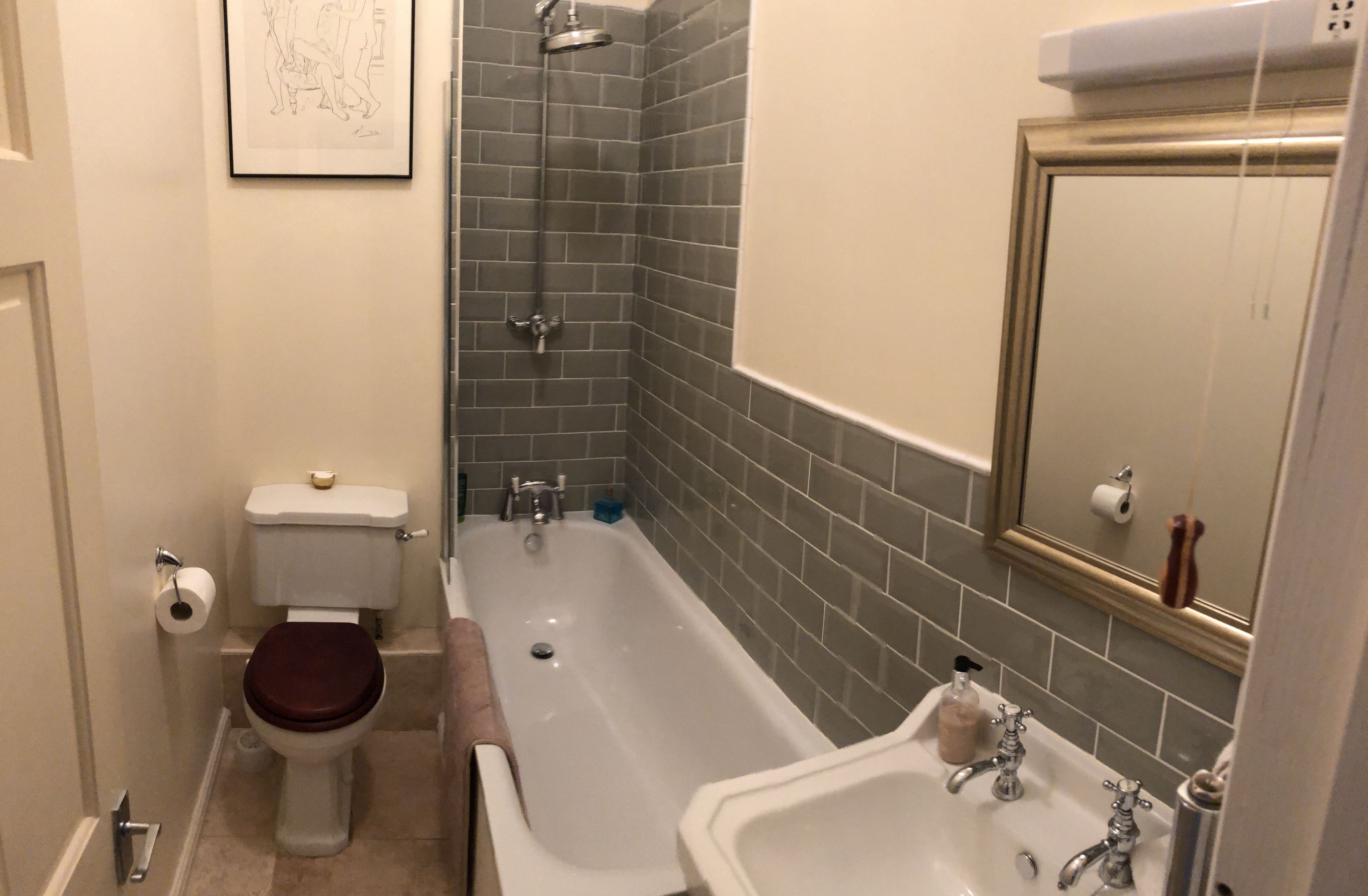 A bathroom with a toilet, bathtub, sink, and a mirror.
