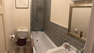 A bathroom with a toilet, bathtub, sink, and a mirror.