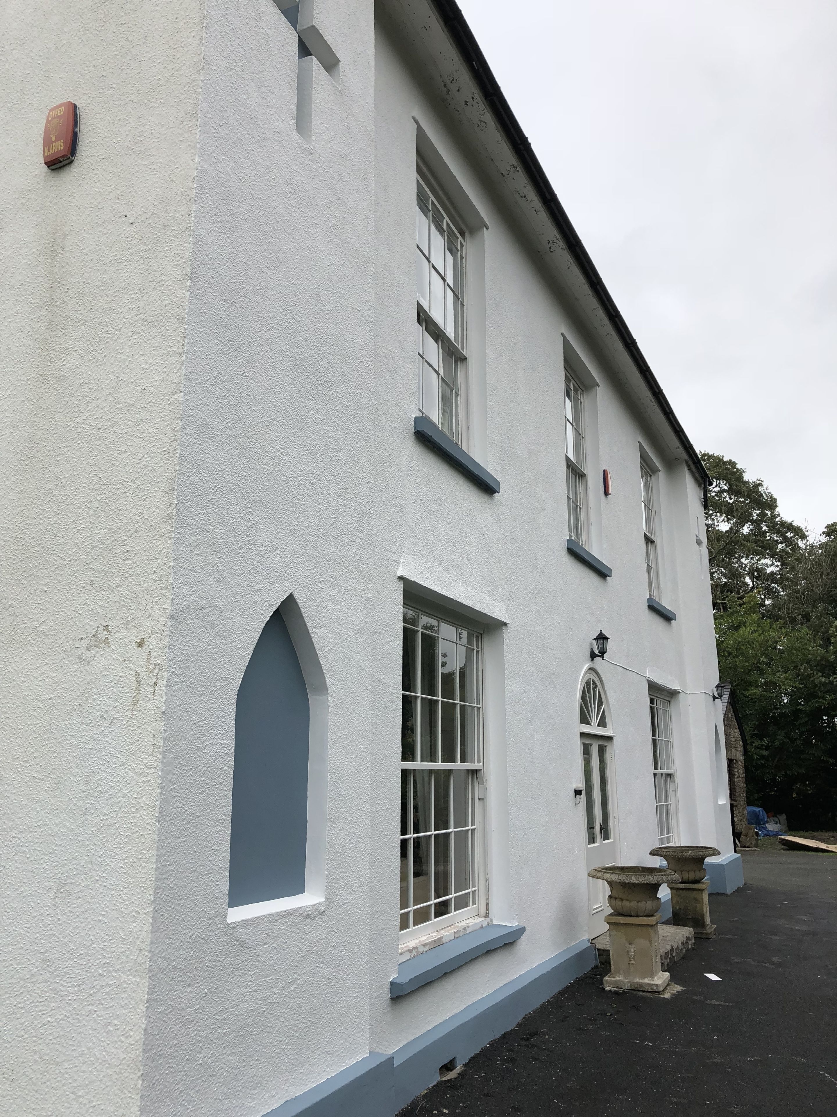 A white building with multiple windows and a small door.
