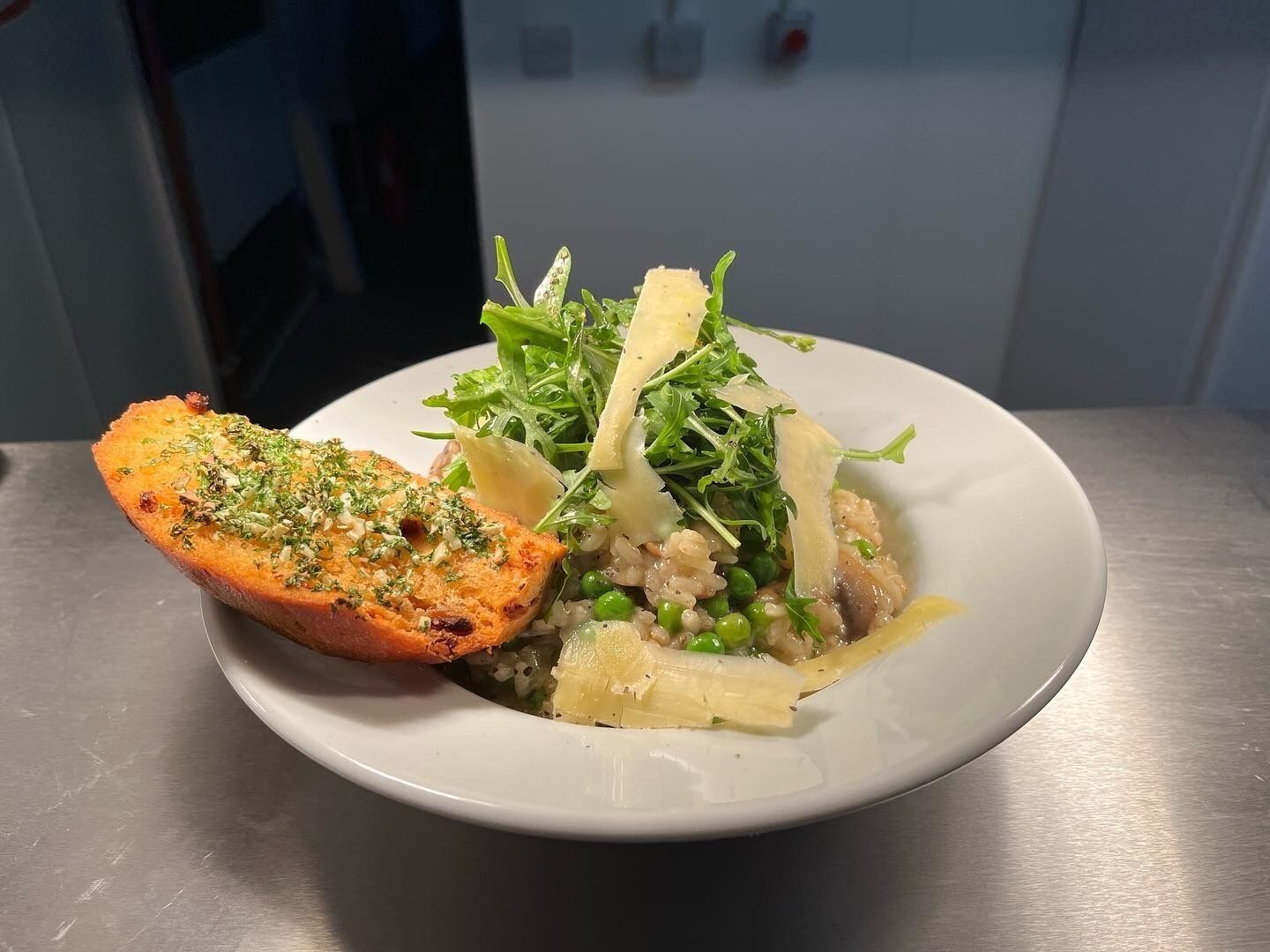 Un plato de comida con pan, vegetales verdes y arroz.