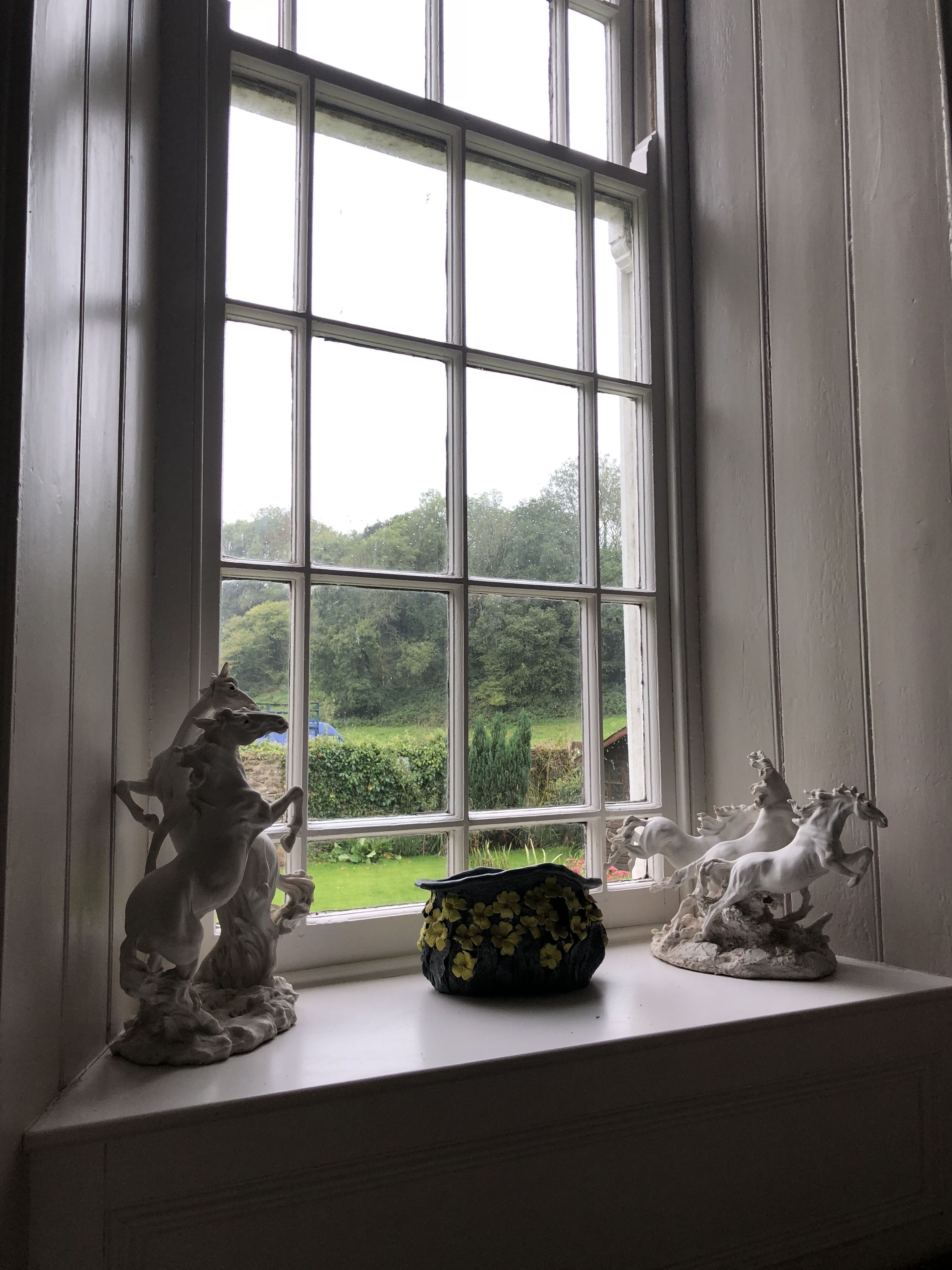 Una ventana con tres estatuas ecuestres en el alféizar.