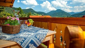 A wooden deck with a table set for dining, overlooking a mountainous landscape. - Chalet unter Weißblauem Himmel (Reit im Winkl)