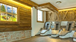 A room with a stone wall, wooden beams, and a large window with a view of a farm. - Chalet unter Weißblauem Himmel (Reit im Winkl)