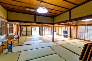 Una habitación tradicional japonesa con esteras de tatami, televisión y techo de madera.