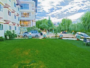 Un barrio residencial con césped cuidado, coches aparcados y un edificio con varios balcones.