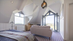 A bedroom with a large bed, a sofa, a window, and a door leading to an outdoor area. - Chyreen@marazion (Marazion)
