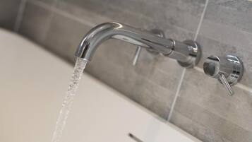 A modern bathroom with a chrome faucet and a tiled wall.