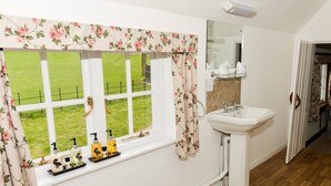 Een badkamer met een raam, een wastafel en toiletartikelen op de vensterbank.