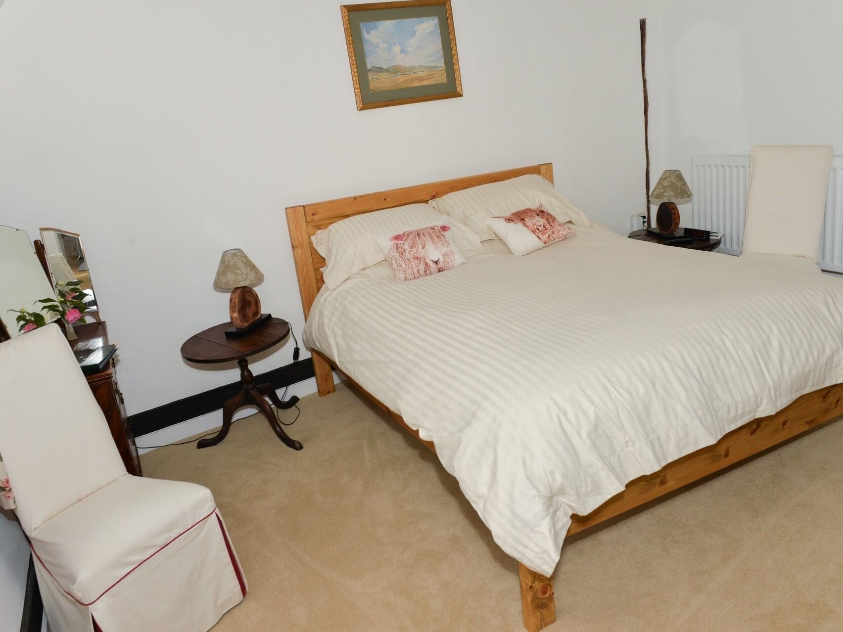 Une chambre à coucher avec un lit en bois, une table de chevet avec une lampe, une chaise et un radiateur.