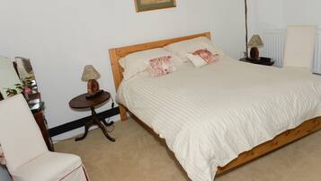 Une chambre à coucher avec un lit en bois, une table de chevet avec une lampe, une chaise et un radiateur.