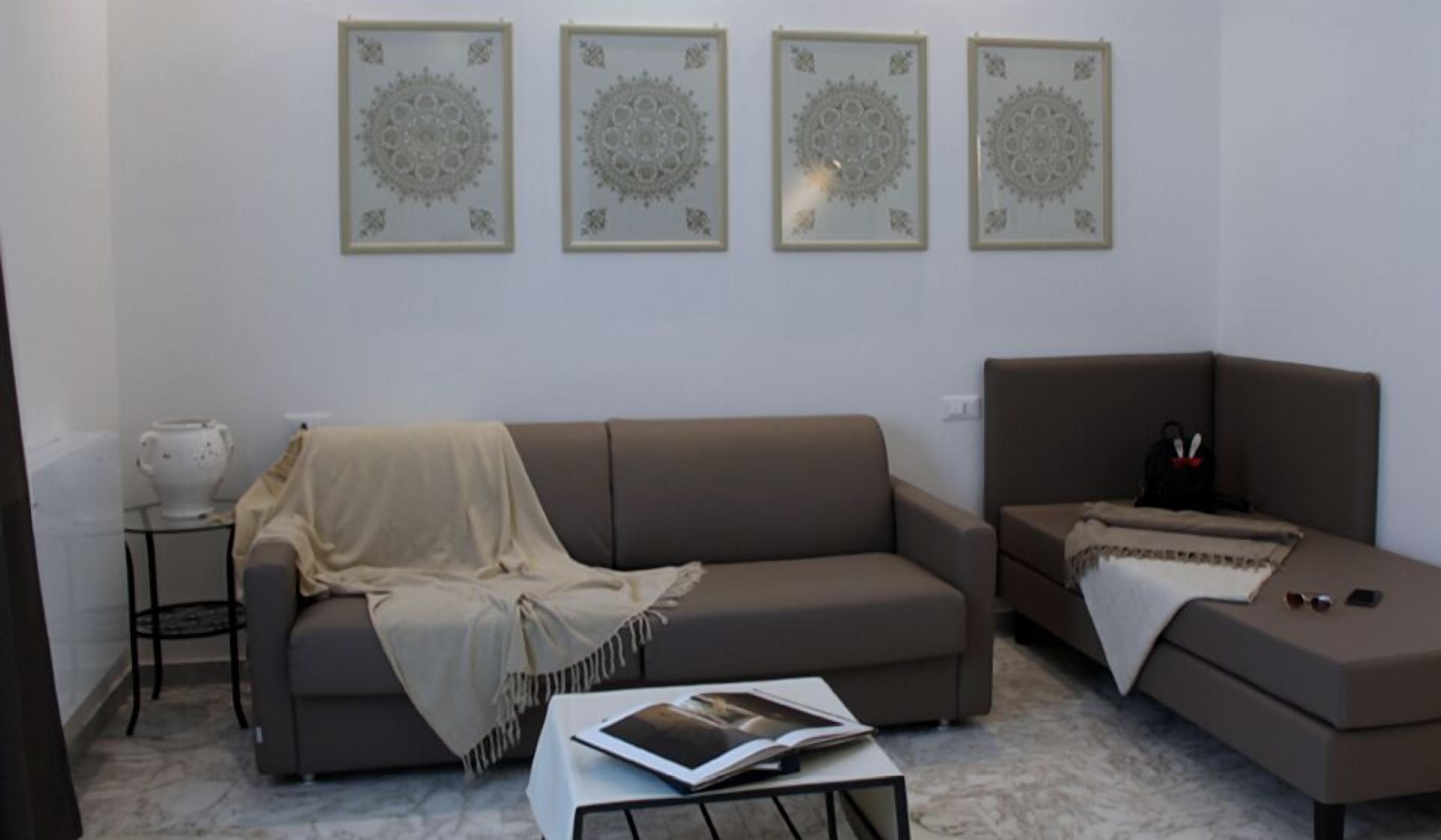 A living room with a sofa, a coffee table with a magazine, and a side table with a teapot.