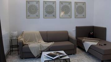 A living room with a sofa, a coffee table with a magazine, and a side table with a teapot.