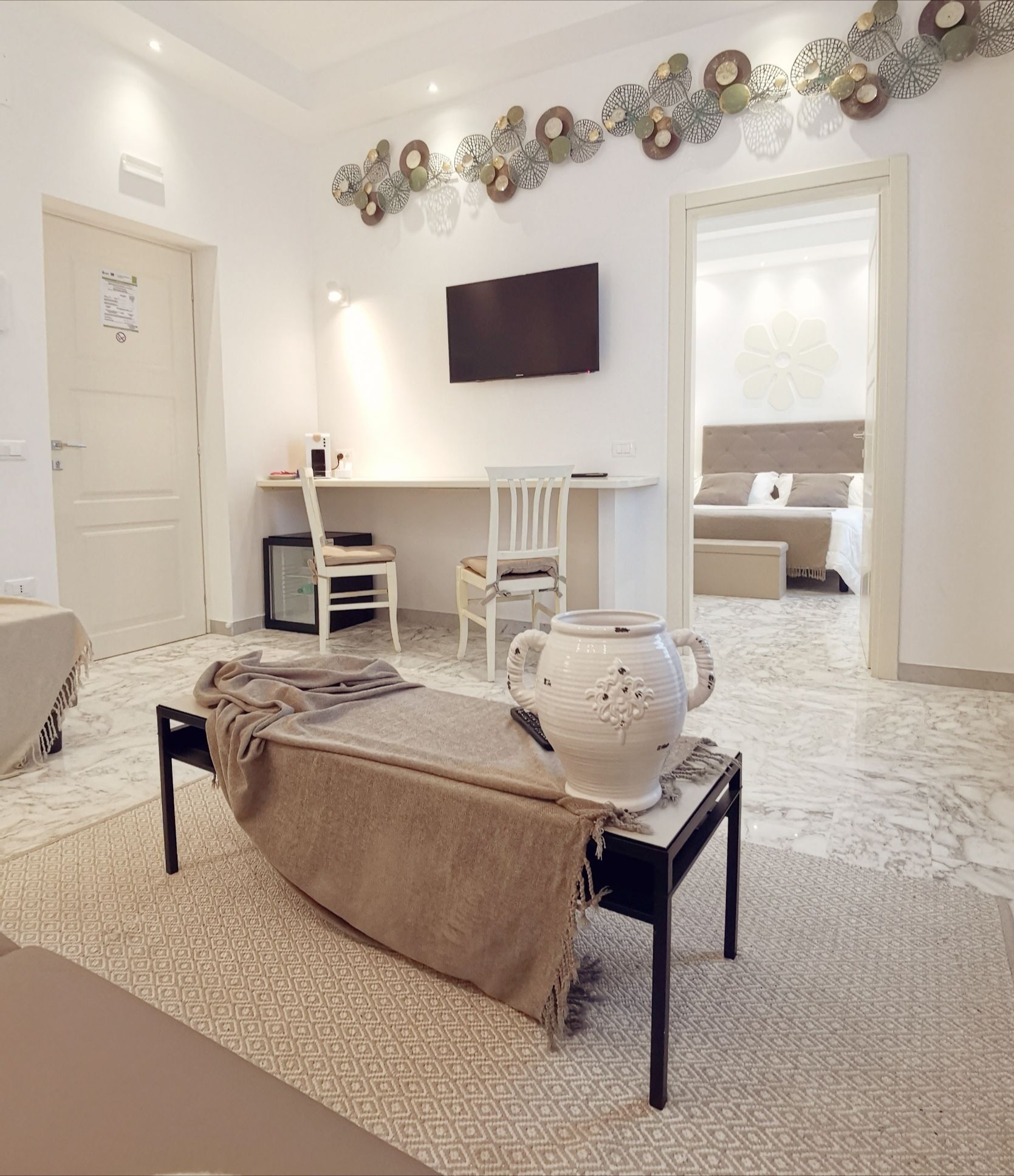 A modern living room with a sofa, a coffee table, a TV, and a decorative wall piece.