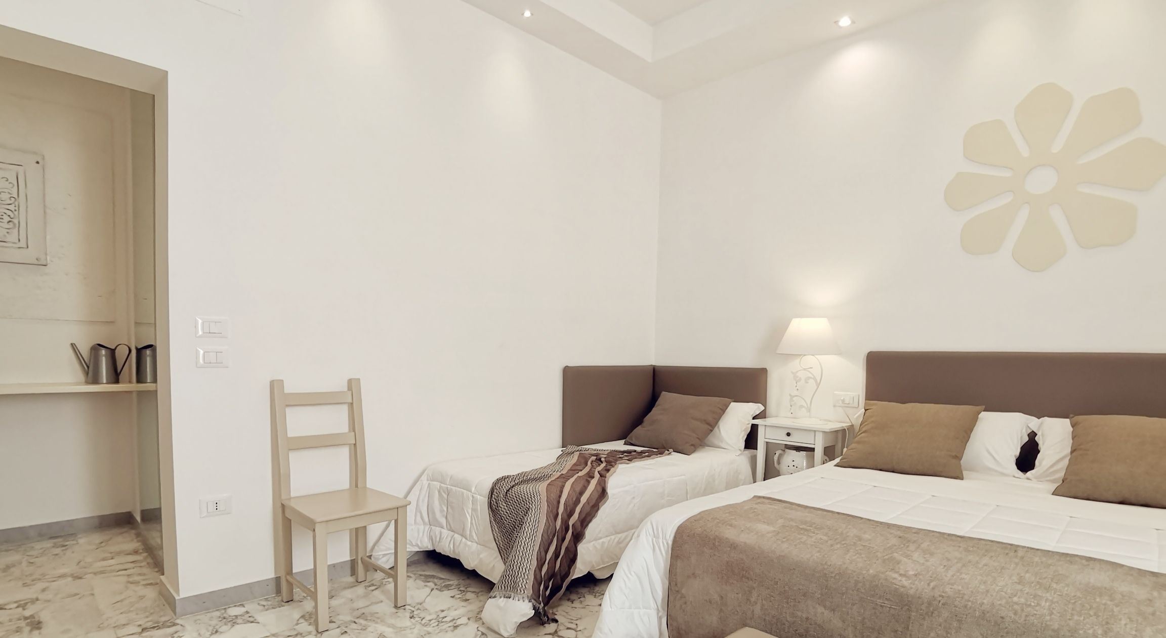A bedroom with two beds, a nightstand, a chair, and a decorative wall piece.