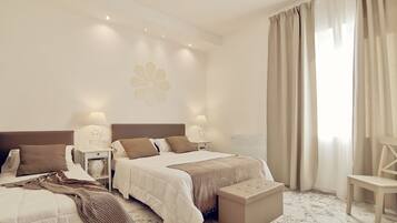 Una habitación de hotel con una cama grande, dos mesitas de noche con lámparas, un banco y una silla.