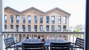 A balcony with a table and chairs, overlooking a row of buildings with balconies.