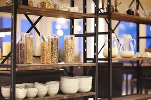 Montaje de bufé con estantes que sostienen recipientes y fuentes llenas de comida.