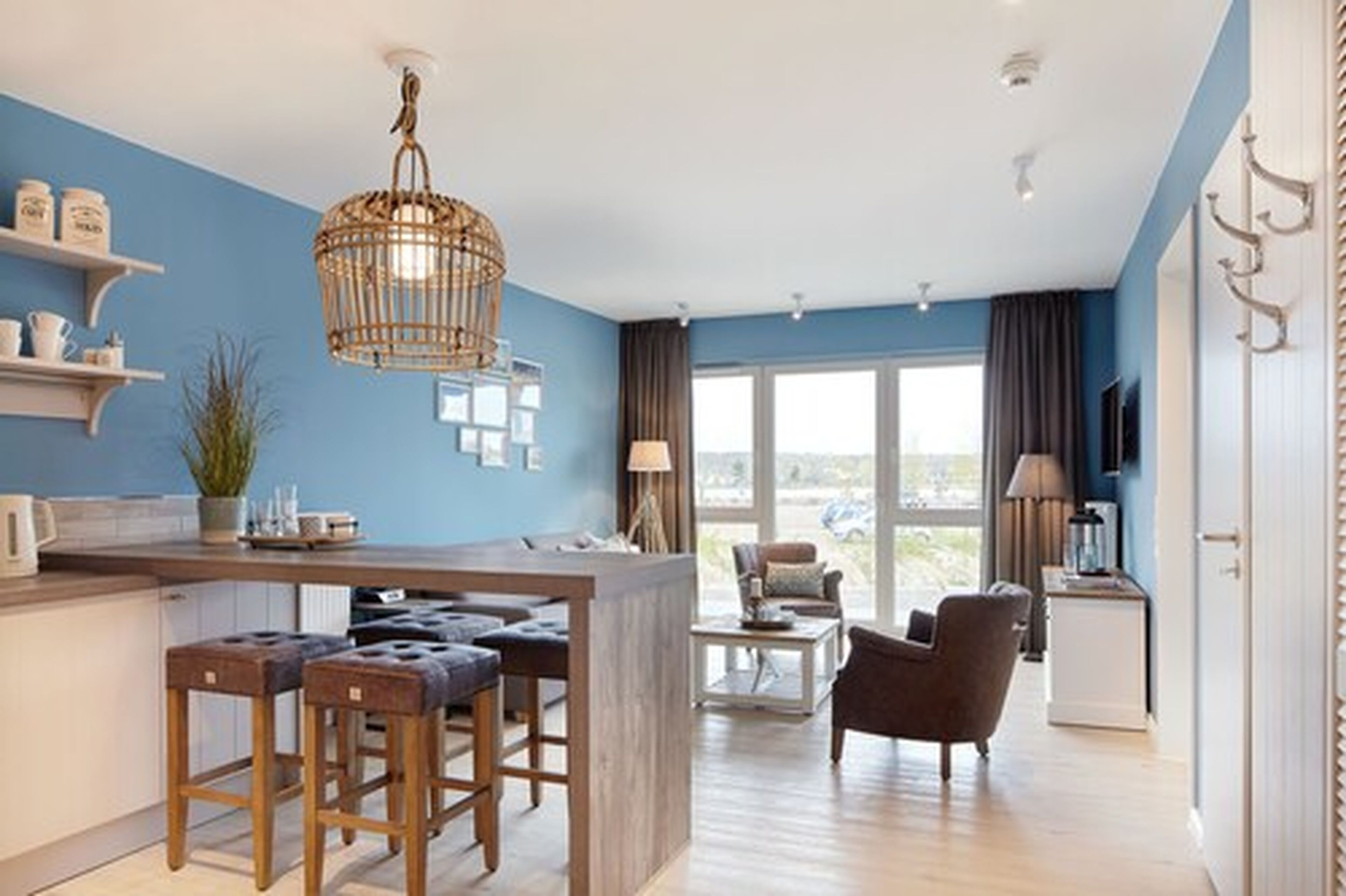 Een moderne keuken met een centraal eiland, barkrukken en een hanglamp.