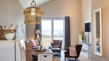 A spacious living room with a large window, a wicker chandelier, and a cozy seating area.