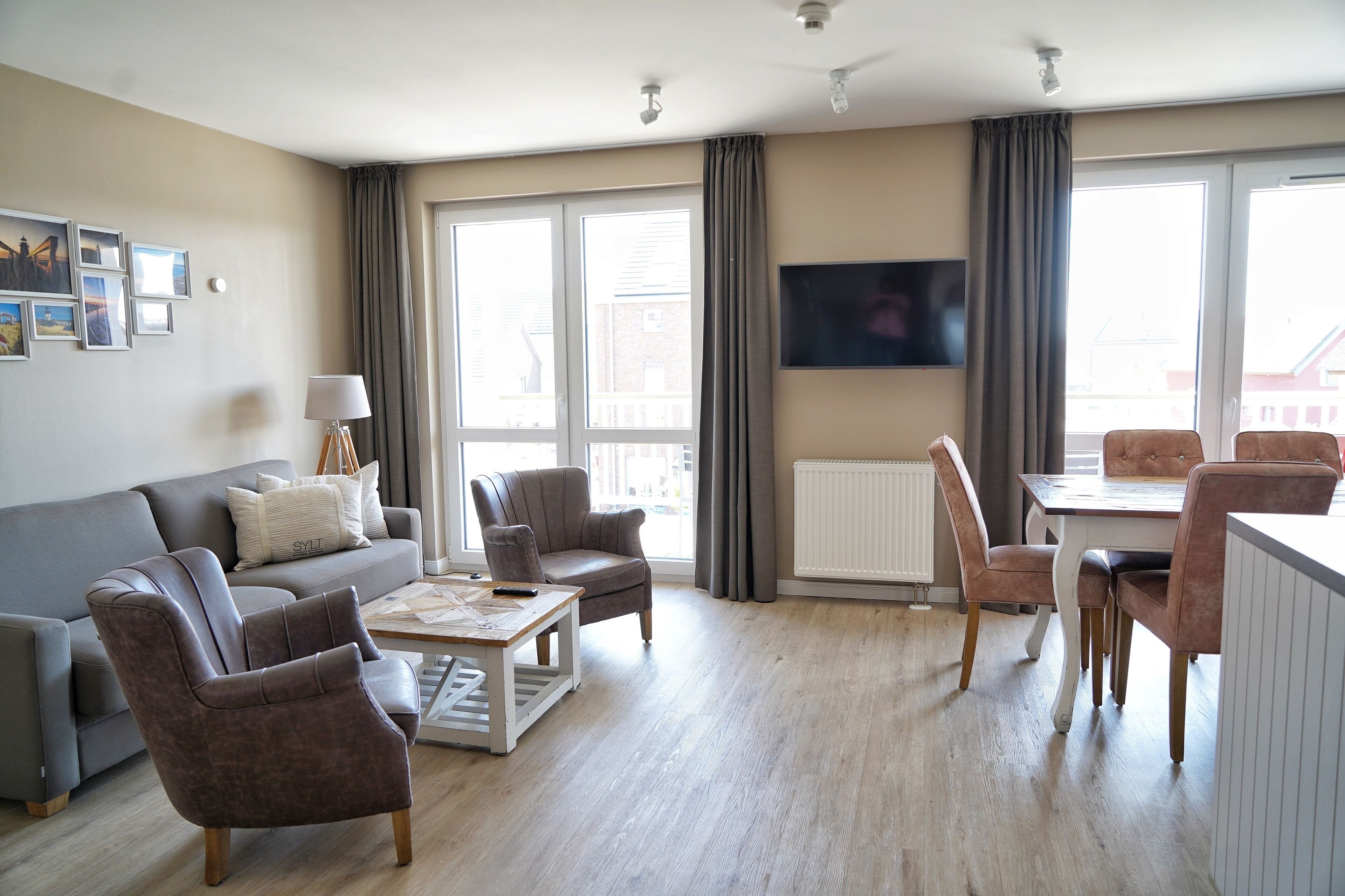A modern living room with a sofa, armchairs, a coffee table, and a dining area with chairs and a table.