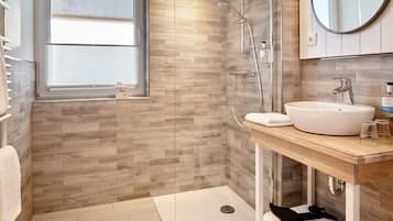 A modern bathroom with a shower, a sink, and a window.