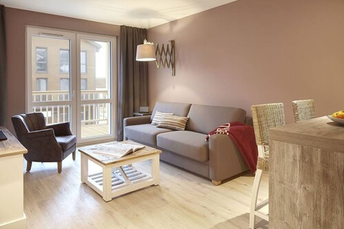 Un salon comprenant un canapé, un fauteuil, une table basse et un coin repas avec une table et des chaises.