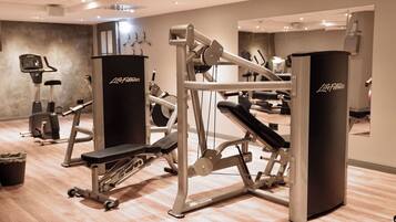 Un gimnasio con diverso equipo de ejercicio, incluyendo una cinta de correr, una elíptica y máquinas de pesas.