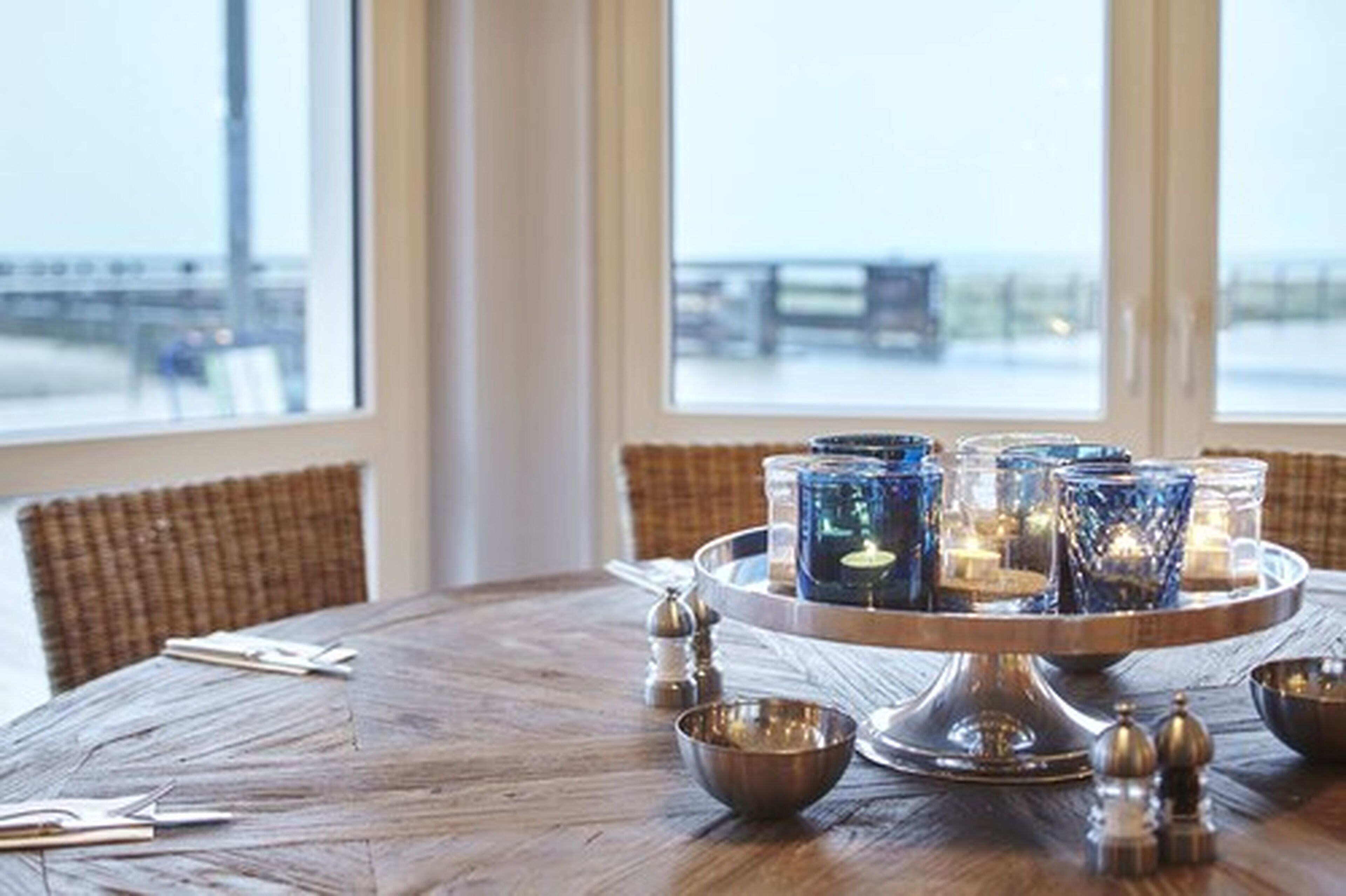 A round wooden table with a candle centerpiece, salt and pepper shakers, and a bowl.