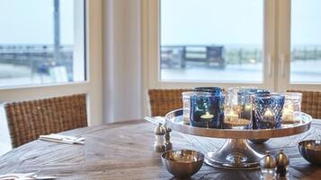 A round wooden table with a candle centerpiece, salt and pepper shakers, and a bowl.