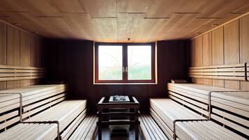 Un sauna avec des bancs en bois et une table, une fenêtre donnant sur la verdure et un plafond en bois.