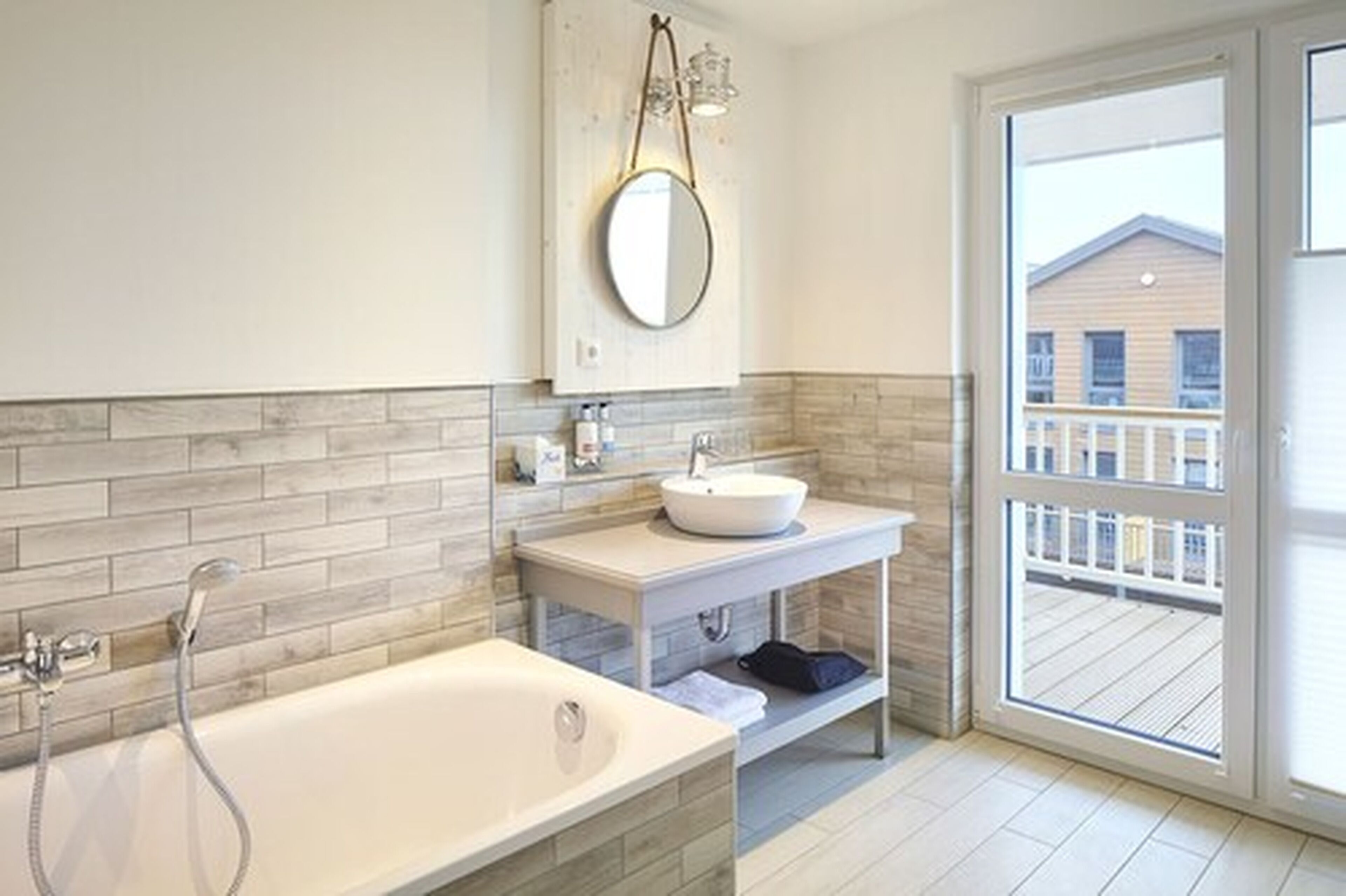 A modern bathroom with a freestanding bathtub, a round mirror, and a white sink with a vessel basin.