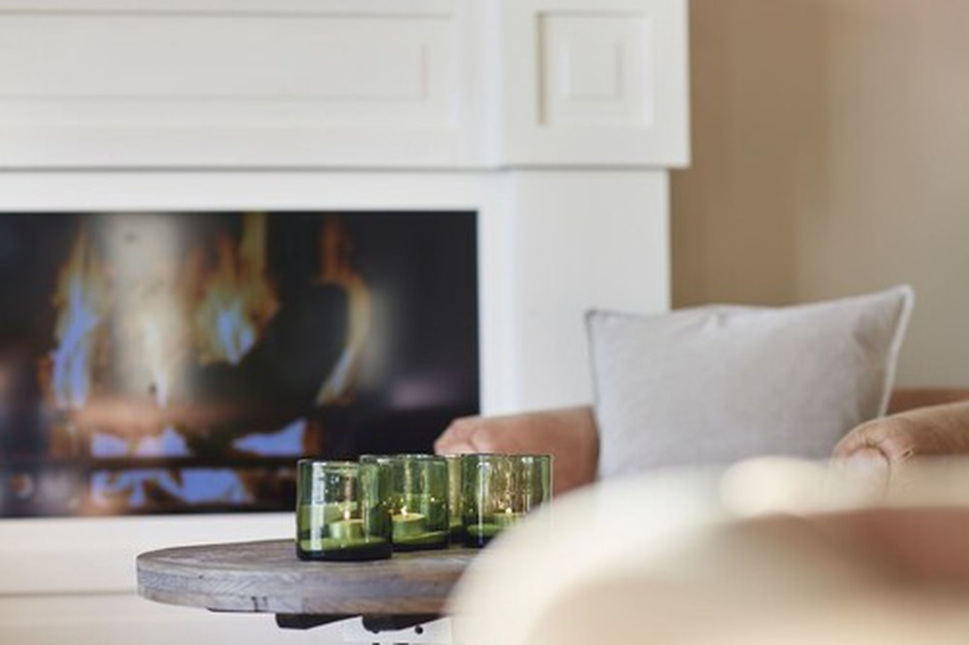 Una sala de estar con chimenea, televisor y una mesa redonda con velas.