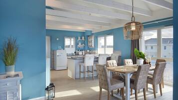 A modern kitchen with a central island, white cabinetry, and a large window providing natural light.
