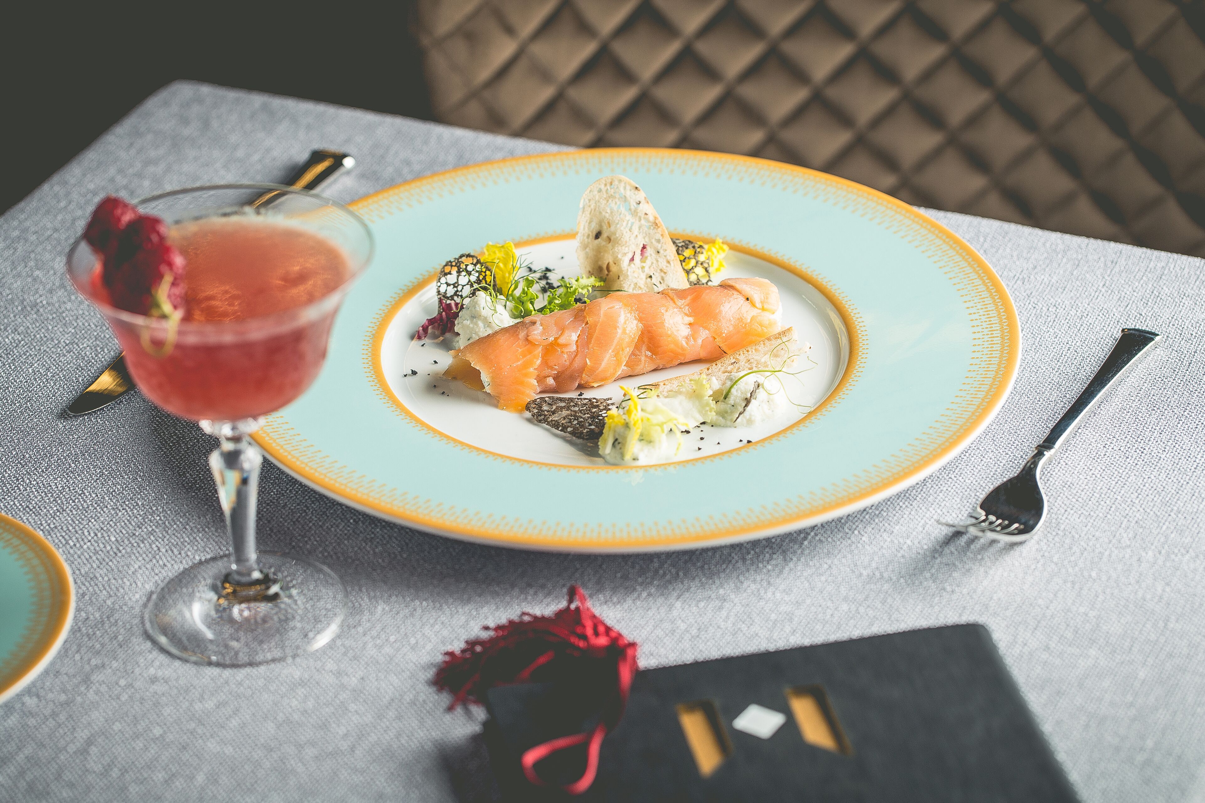 A table with a plate of food, a glass of red drink, and a fork.