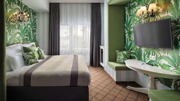 Una habitación de hotel con cama, televisión, una mesita y ventana con cortinas.
