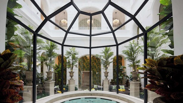 A pool area with a glass ceiling, surrounded by lush plants and columns. - Mystery Hotel Budapest, Preferred Hotels & Resorts  (Budapest)