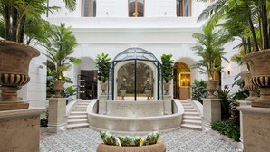 A spacious courtyard with a central glass gazebo, surrounded by potted plants and a patterned floor. - Mystery Hotel Budapest, Preferred Hotels & Resorts  (Budapest)