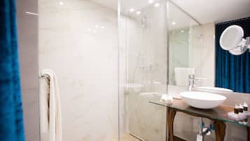 A modern bathroom with a glass shower enclosure, a white sink, and a large mirror.