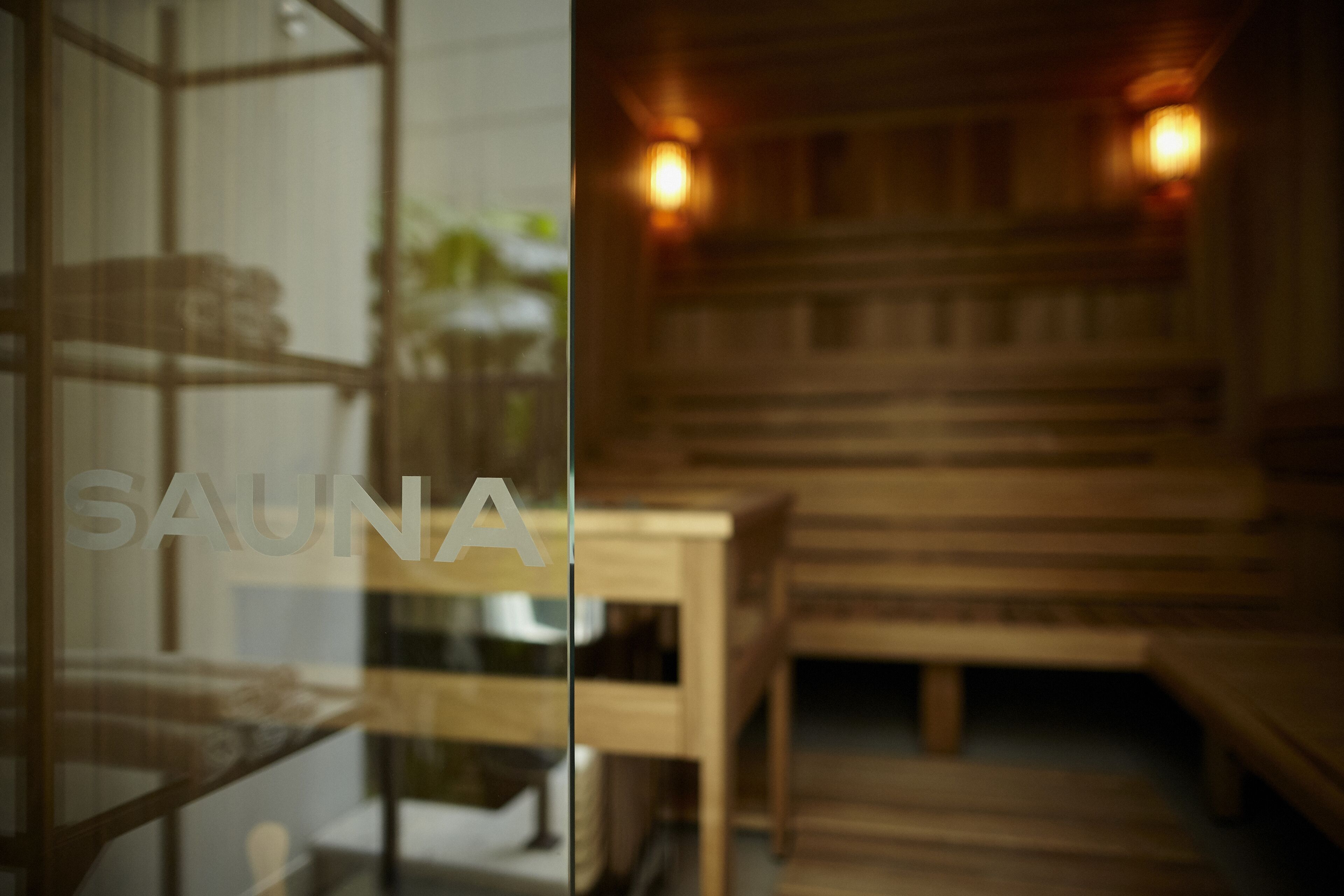 A sauna room with wooden benches and a glass partition.