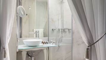A modern bathroom with a glass sink, a large mirror, and a glass-enclosed shower.