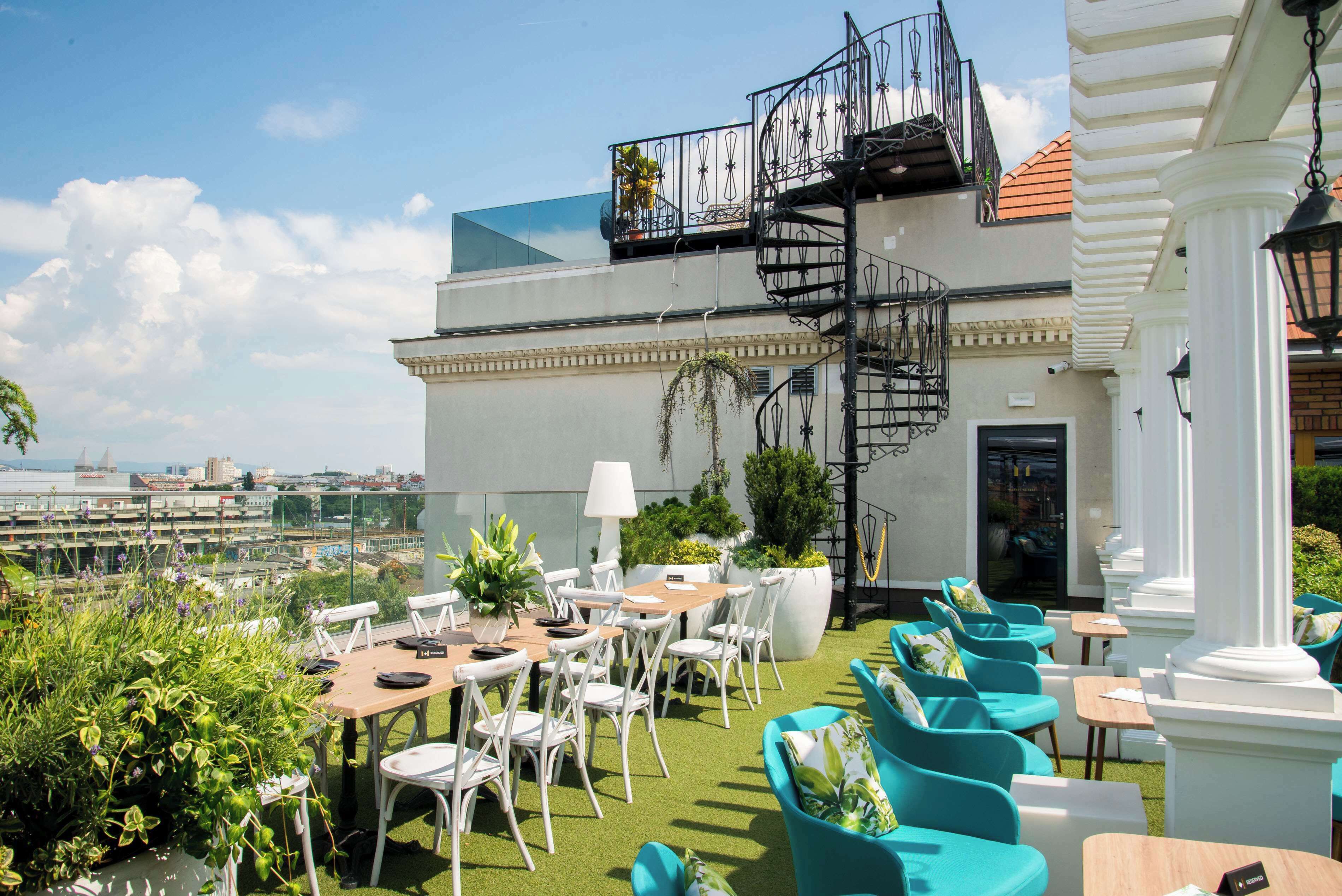 A rooftop terrace with outdoor seating, a spiral staircase, and a view of the city.