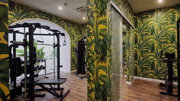 A gym with wooden flooring, exercise equipment, and a tropical wallpaper design.